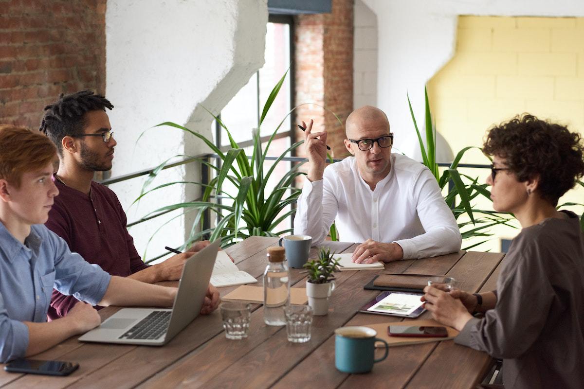 pessoas conversando em uma mesa, como se estivessem em uma reunião de trabalho