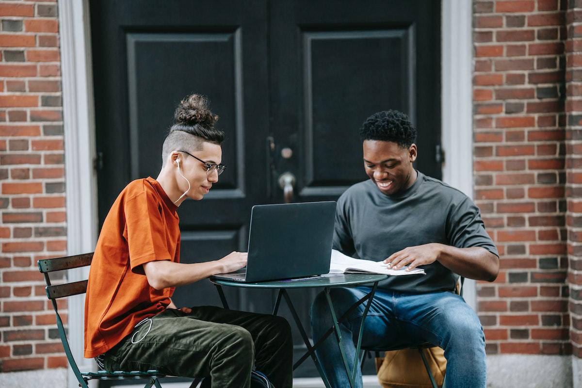 dois jovens sentados, estudando ao ar livre