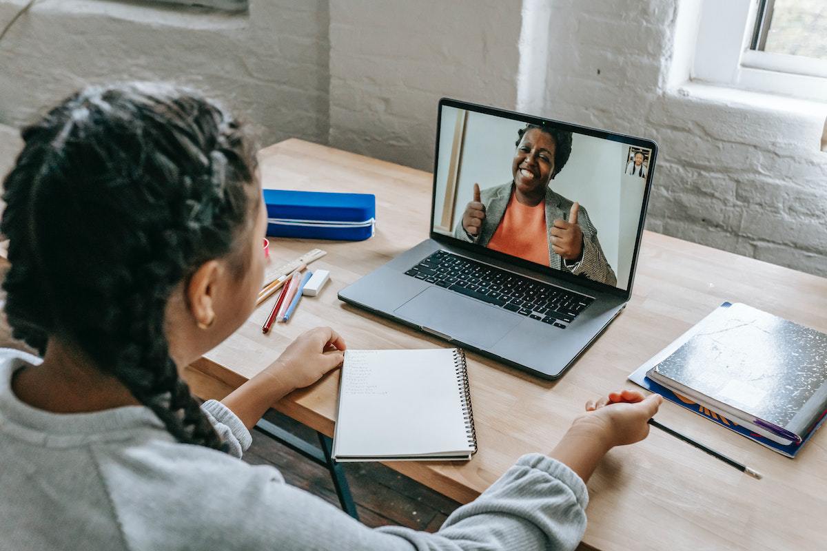 mulher sentada, estudando com a ajuda de um caderno e um laptop