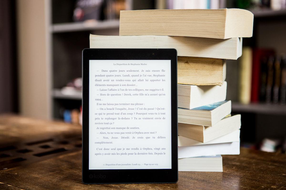 kindle na frente de um bloco de livros físicos