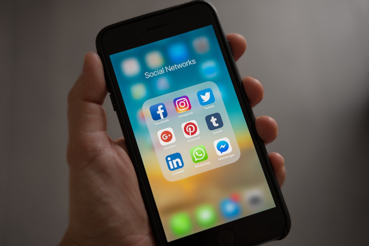 Estratégia visual para redes sociais: A imagem mostra uma mão segurando um smartphone e na tela estão alguns aplicativos. 