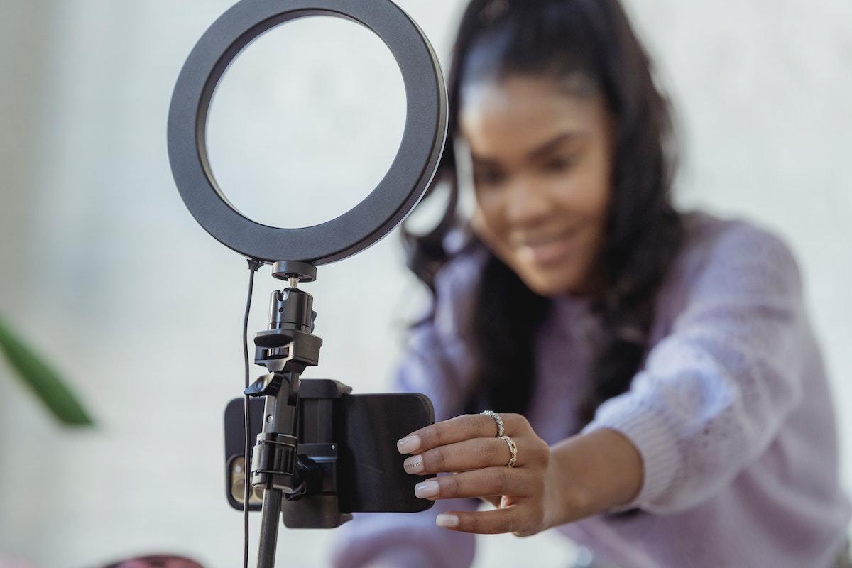 mulher gravando vídeo com a ajuda de um celular e uma ring light