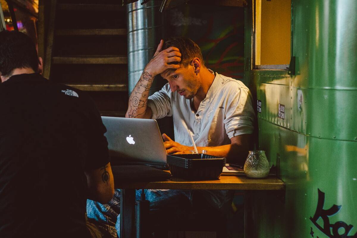 Homem com computador em um bar: Marketing invisível Marketing invisível: A imagem mostra um home jovem usando um computador em um bar