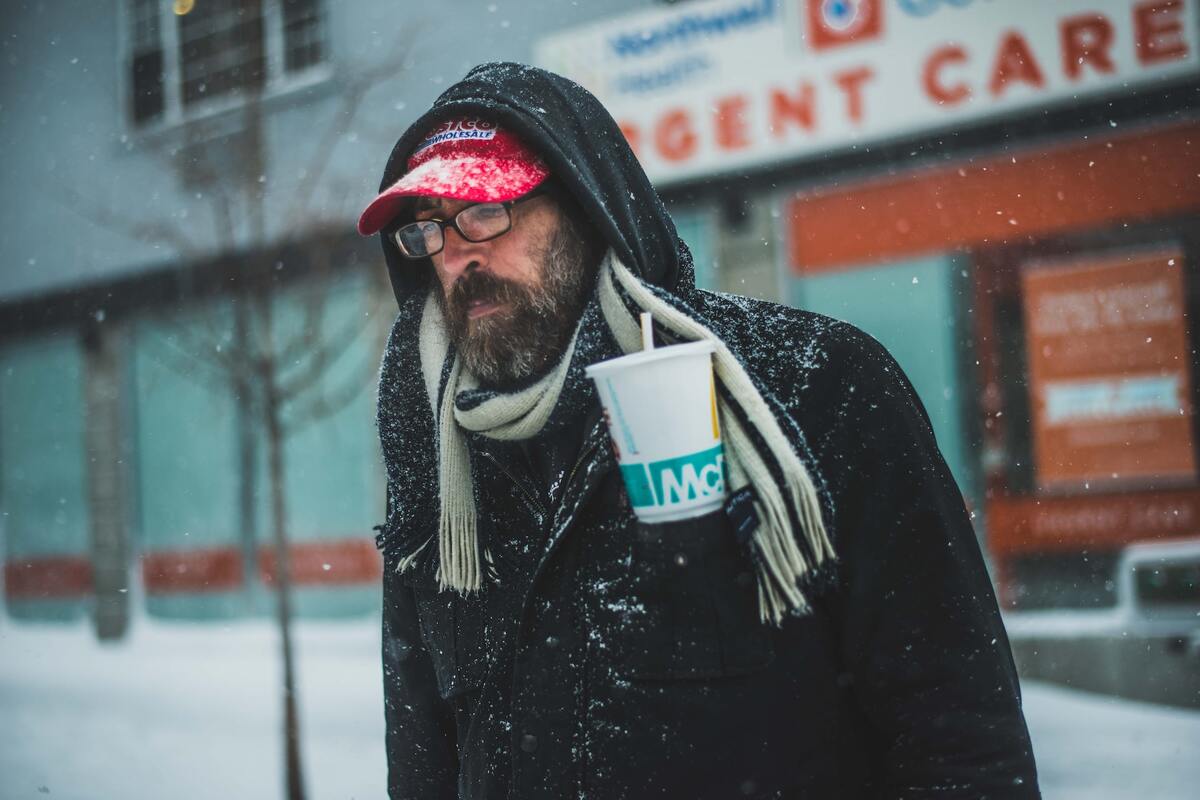 Homem com copo do Mc Donald: Marketing Invisível Marketing invisível: A imagem mostra um homem mais velho com roupa de frio e o mesmo está segurando um copo de refrigerante do Mc Donald