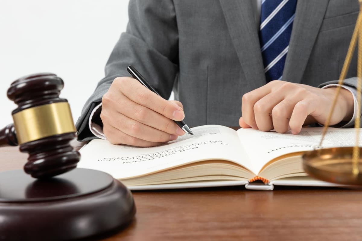 Juiz estudando um livro: Marketing jurídico Marketing jurídico: A imagem mostra um juiz estudando algo em em livro e próximo a ele um martelo de juiz.