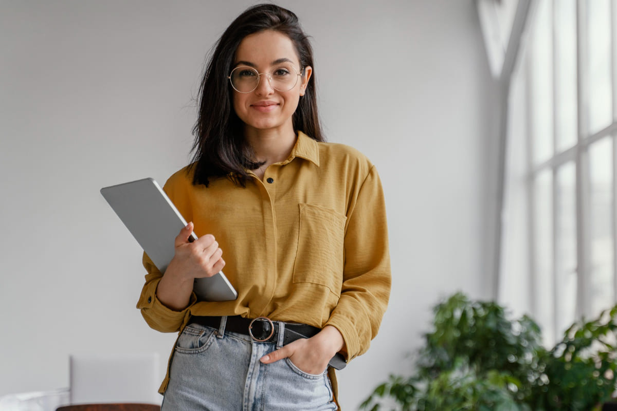 Mulher segurando um tablet: Marketing para mulheres Marketing para mulheres: A imagem mostra uma mulher olhando para frente enquanto segura um tablet. Ao fundo estão algumas plantas