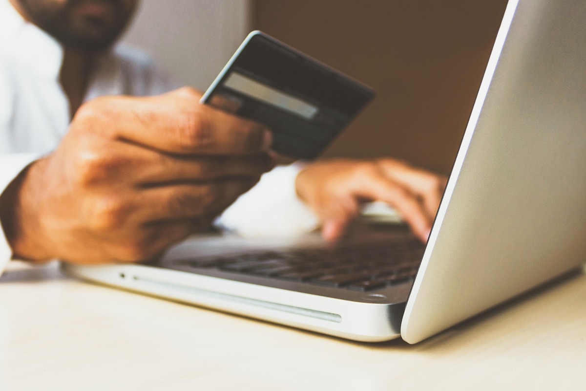 compras online: native ads homem segurando um cartão enquanto usa o notebook