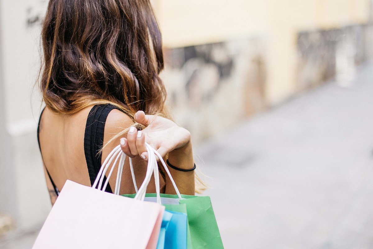 Pós - venda: A imagem mostra uma mulher jovem com algumas sacolas de compras nas mãos. 
