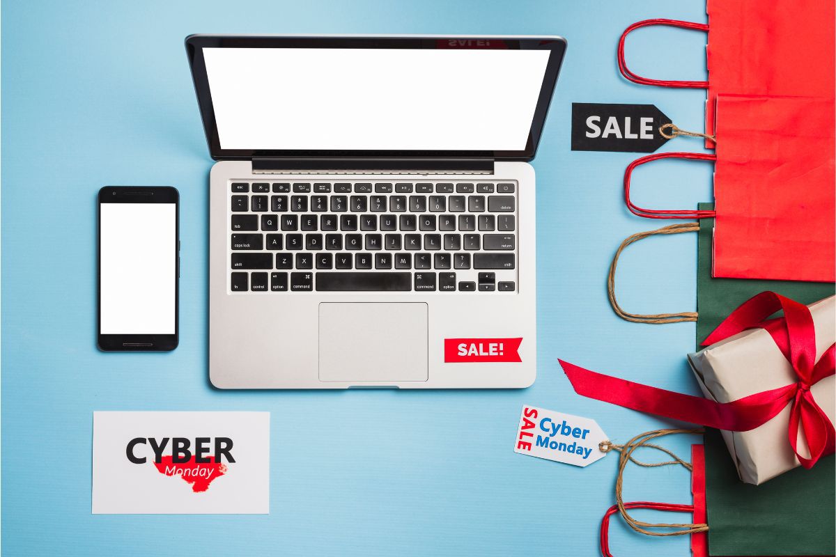 sale: promoção no e-commerce notebook do lado de um celular e sacolas com o nome sale