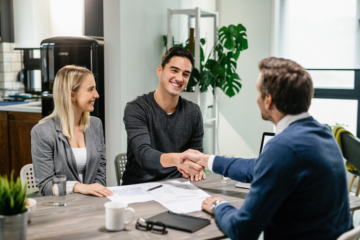 Pessoas em reunião fechando contratos: Retenção de clientes para agências Retenção de clientes para agências: A imagem mostra uma reunião de trabalho, onde pessoas estão apertando as mãos indicando o fechamento de algum contrato
