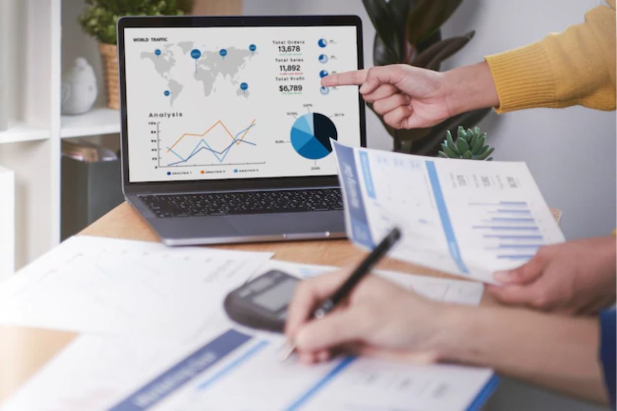 análise de relatórios: roi das mídias sociais pessoas trabalhando e analisando relatórios e gráficos sendo mostrados no computador