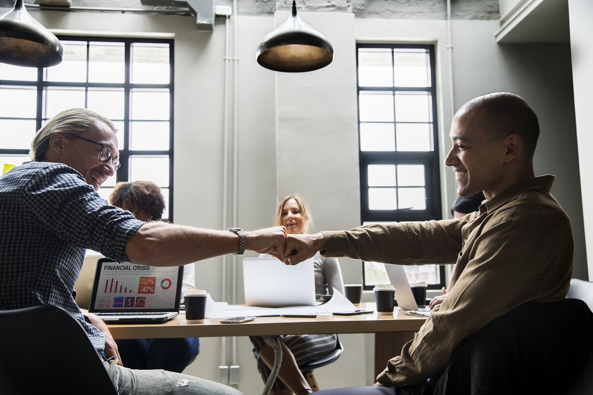 Time de vendas para agências: A imagem mostra algumas pessoas em um escritório e duas delas estão se cumprimentando. 