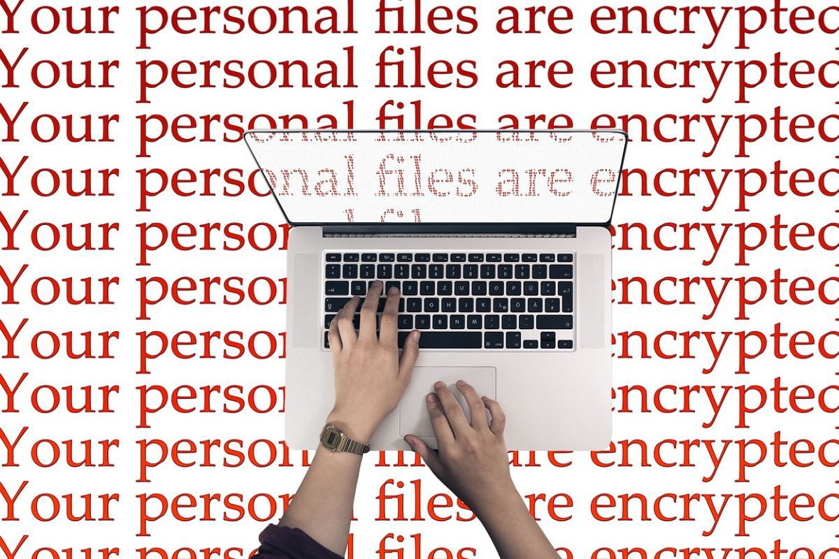 homem usando laptop com uma mensagem em inglês que diz seus arquivos pessoas são criptografados