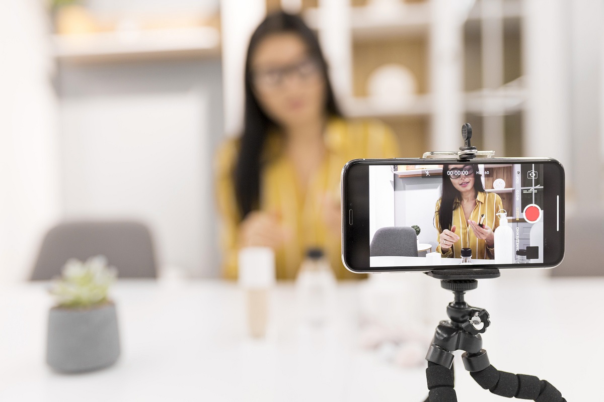 Mulher fazendo um tutorial de maquiagem: Vídeos para redes sociais Vídeos para redes sociais: a imagem mostra uma mulher jovem fazendo um tutorial de maquiagem.