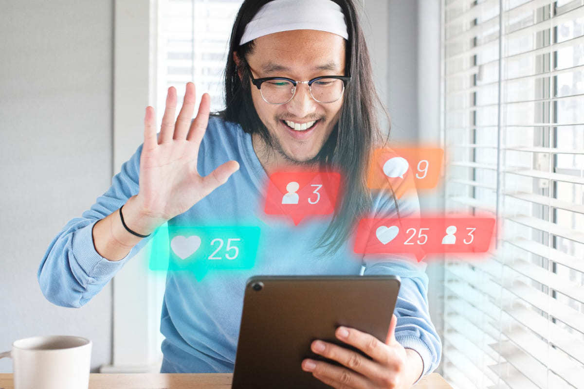 Homem com tablet na mão em interação de redes sociais como forma de Abrangência do conteúdo com símbolos no ar saindo da tela em montagem