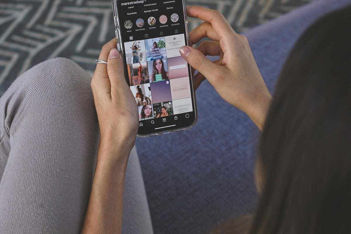 Rede social: Atrair clientes Mulher com celular na mão usando aplicativo do Instagram e analisando foto de um perfil na rede social