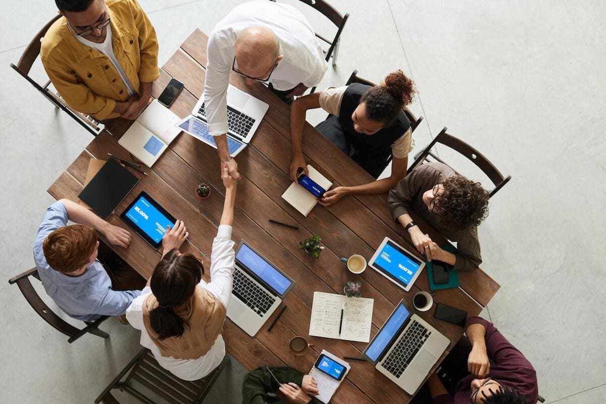 Reunião: Atrair clientes Pessoas em reunião para Atrair clientes em local de trabalhando usando aparelhos como tablet e notebook ao redor de mesa e madeira