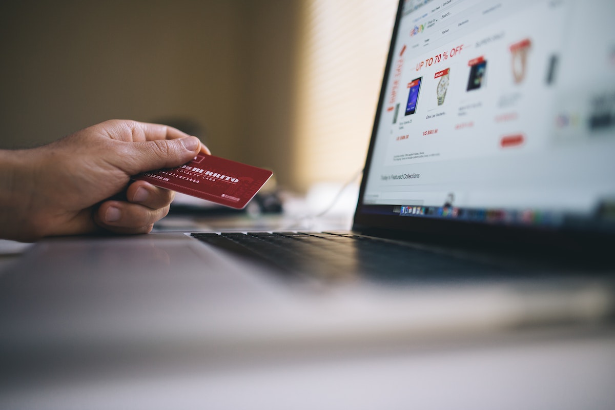 CRM para e-commerce: a imagem mostra um homem com um cartão de crédito fazendo uma compra online 