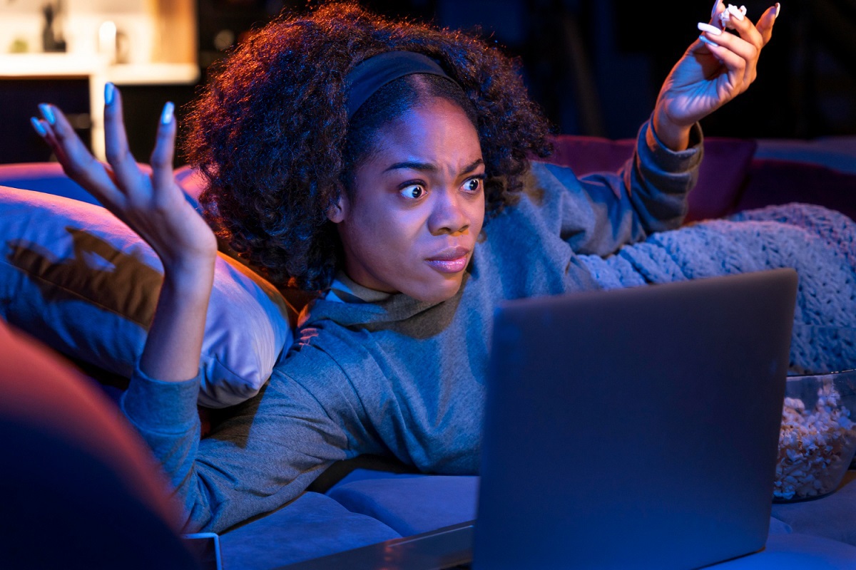 Surpresa: Clickbait Mulher deitada em sofá diante de notebook em mesa de centro e com ar de surpresa