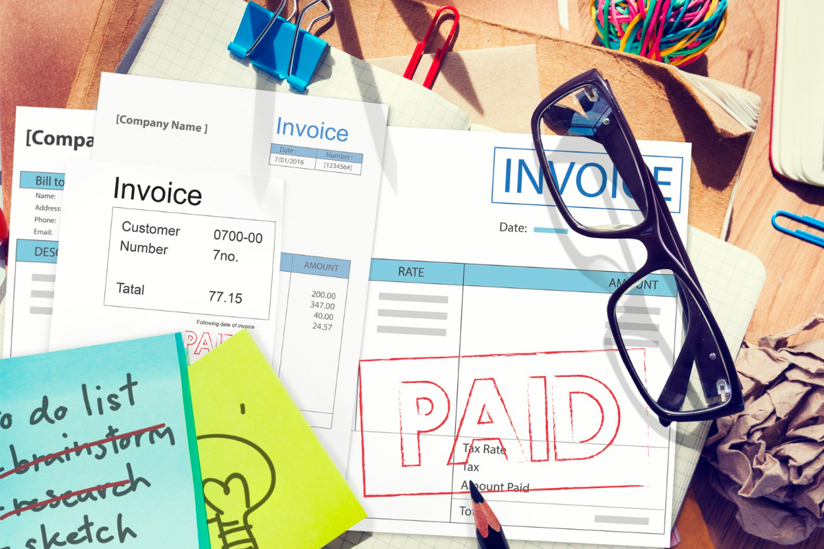 Escritório: Emissão de nota fiscal Dados impressos em inglês com post-its anotados na mesma língua com objetos de escritório e óculos de grau dobrado sobre mesa