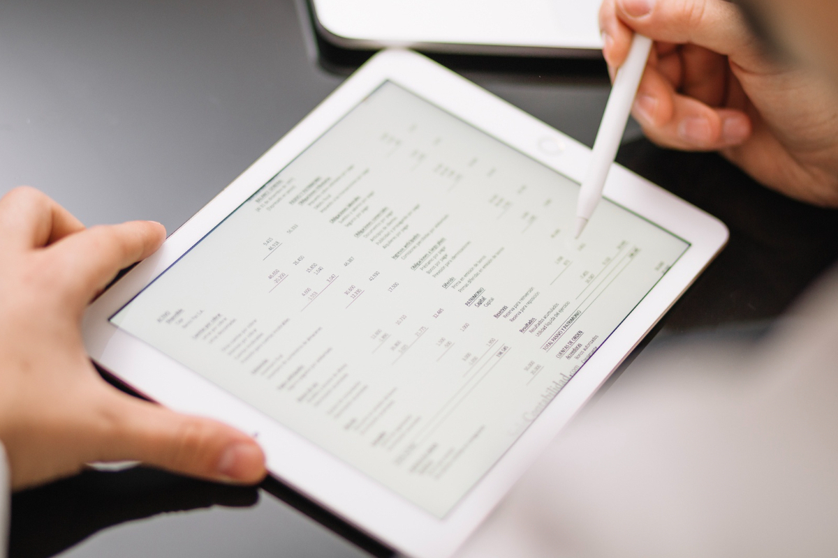 Pedido: Emissão de nota fiscal Pessoa analisando pedido em tablet usando caneta para telas touch para em seguida fazer Emissão de nota fiscal