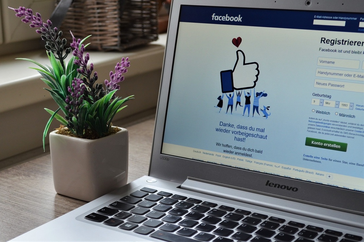 Notebook: Fazer um vídeo no Facebook Notebook sobre mesa de madeira em tela de login ao lado de planta de interior