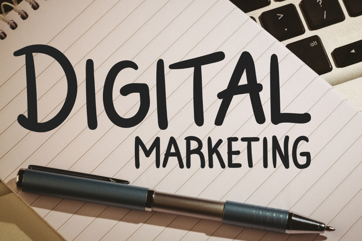 Folha de caderno com caneta sobre a mesma com nome Digital Marketing sobre calculadora