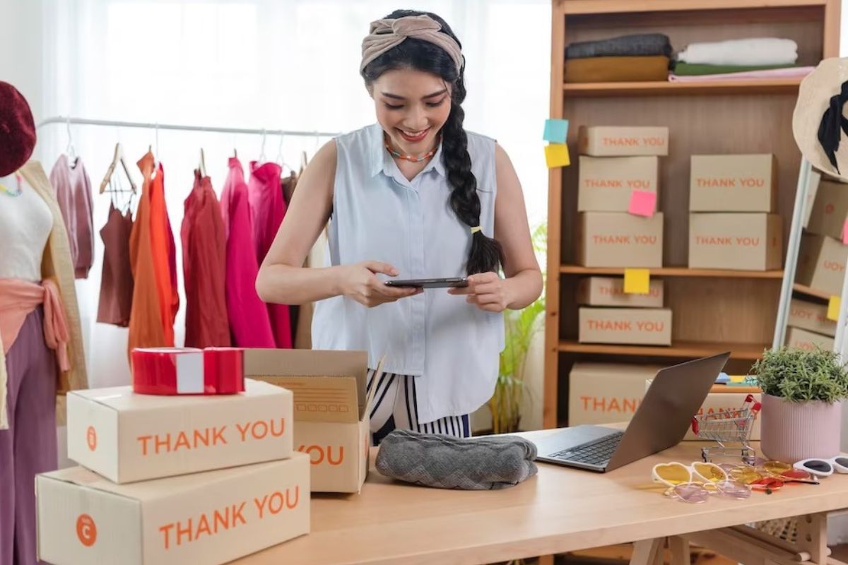 Loja: Gerar leads com Instagram Mulher tirando foto de produto em balcão de loja de roupas e acessórios