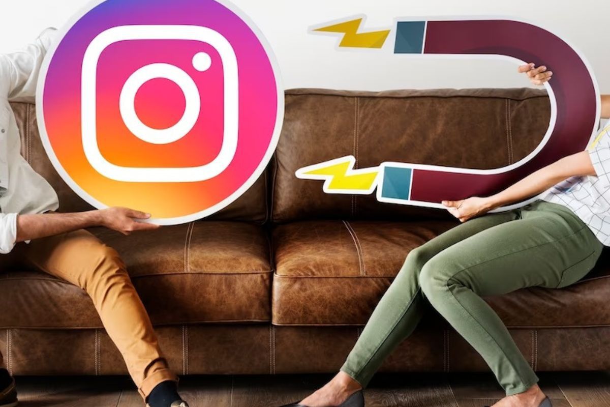 Atração: Gerar leads com Instagram Homem sentado em sofá segurando placa grande com símbolo do Instagram ao lado de mulher com placa com símbolo de imã apontado para a outra placa como representação de atração de leads