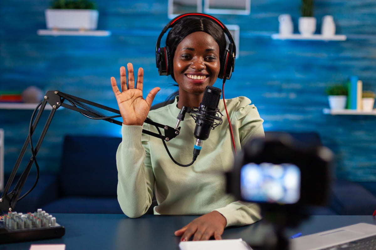 Vídeo: Gerenciar canal do YouTube Mulher usando microfone sobre mesa preta com câmera diante da mesma enquanto grava vídeo sorridente para Gerenciar canal do YouTube