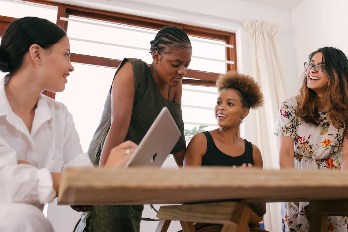 Quatro mulheres em local de trabalho reunidas debatendo temas de Gestores
