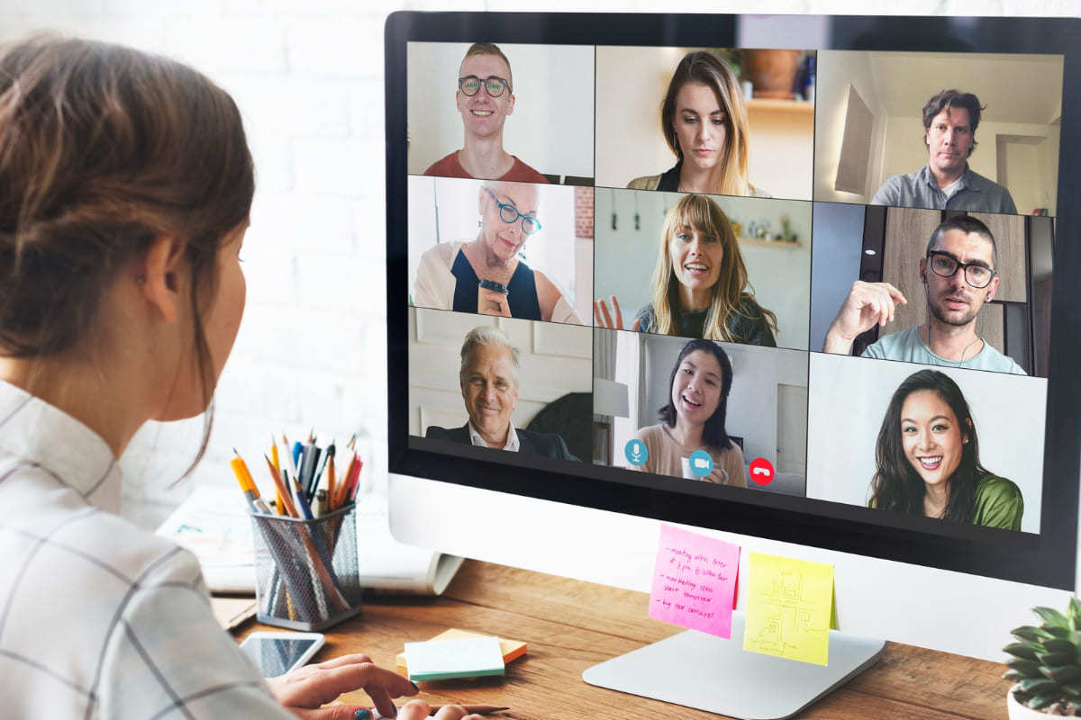 Computador: Hacking sales Mulher em reunião online com outras pessoas usando computador sobre mesa de madeira com itens de escritório espalhados ao seu redor