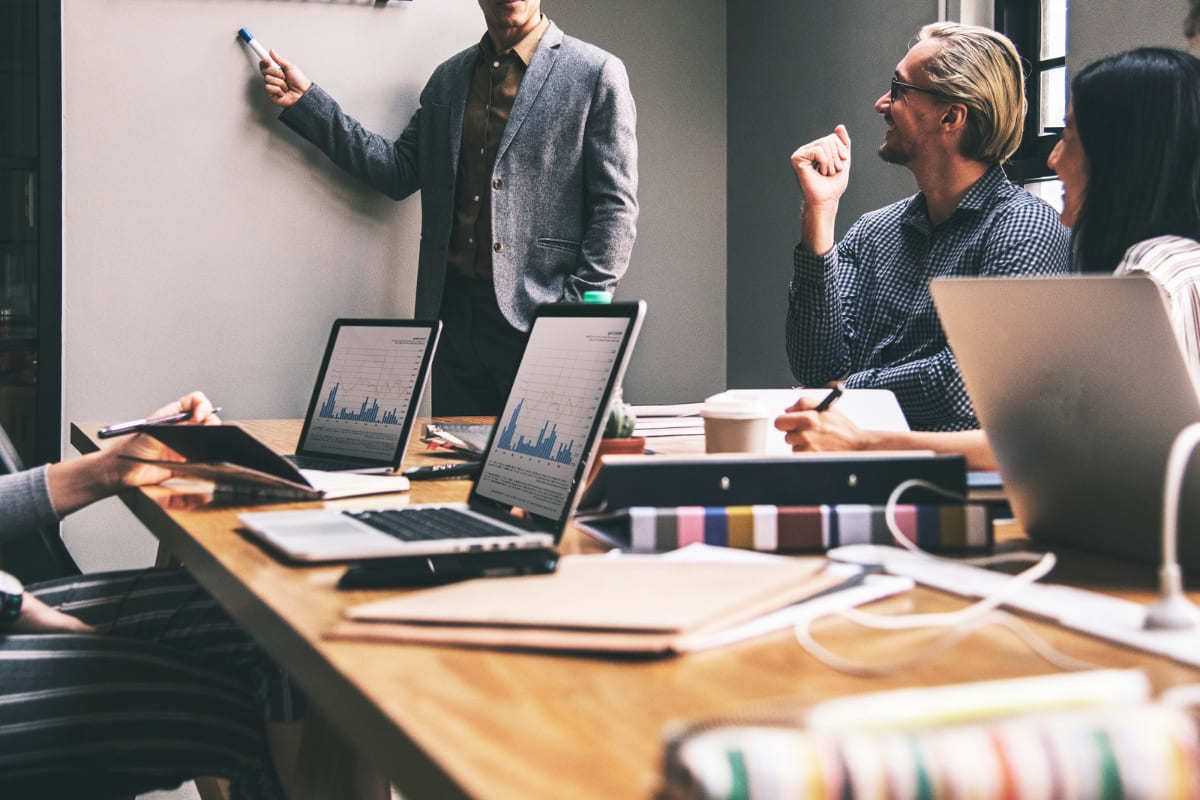 Reunião: Hacking sales Reunião com pessoas debatendo Hacking sales e líder de pé diante dos mesmos falando sobre dados