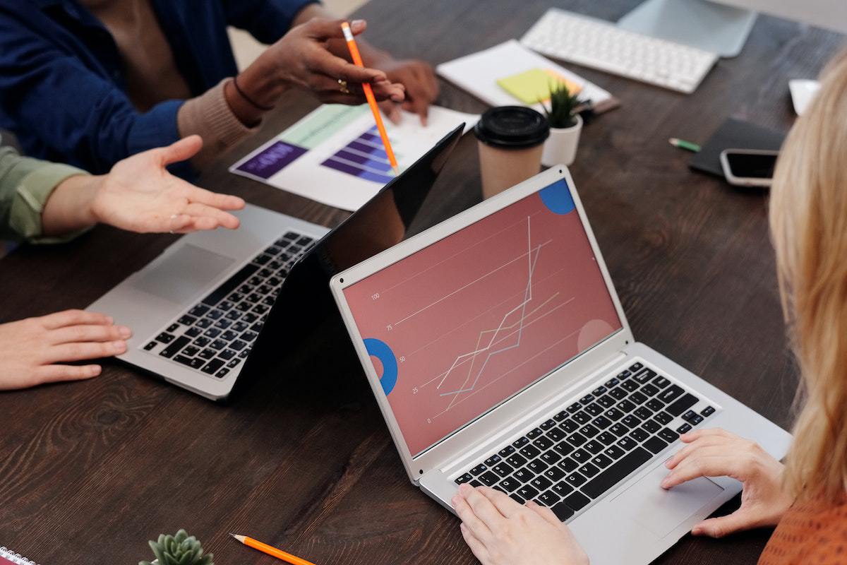 Pessoas usando notebook em reunião com gráficos de Matemarketing