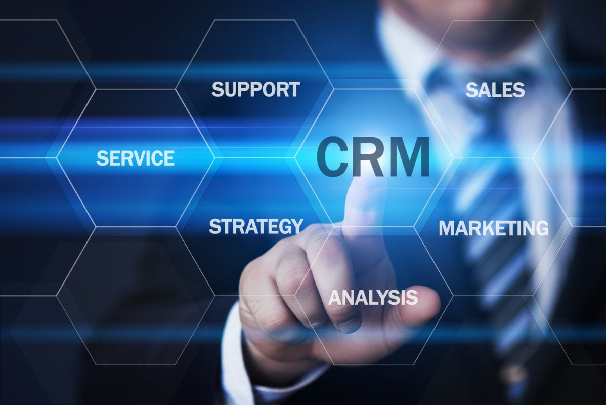 Homem com dedo indicador na mão direita esticado como se clicasse em algo e montagem gráfica à frente da foto com tela em holograma e termos de Oracle CRM e sigla no centro da imagem, onde o homem clica