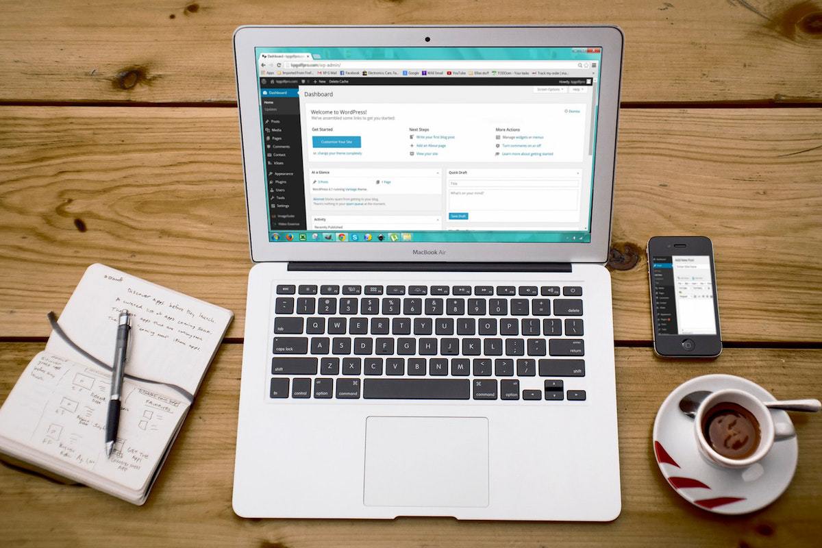 Notebook sobre mesa de madeira e ao lado de xícara de café e agenda em tela inicial do WordPress