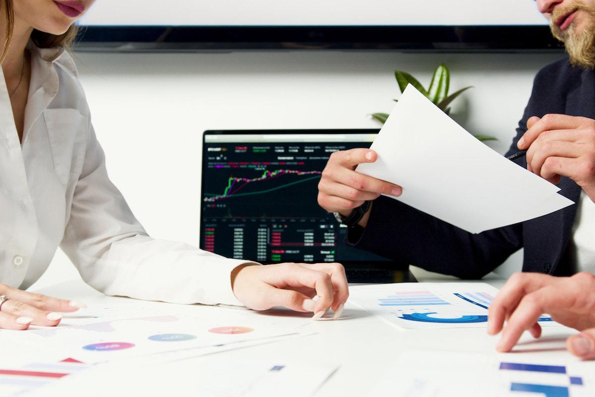 Homem e mulher analisando dados em folha impressa em local de trabalho como Profissional de marketing