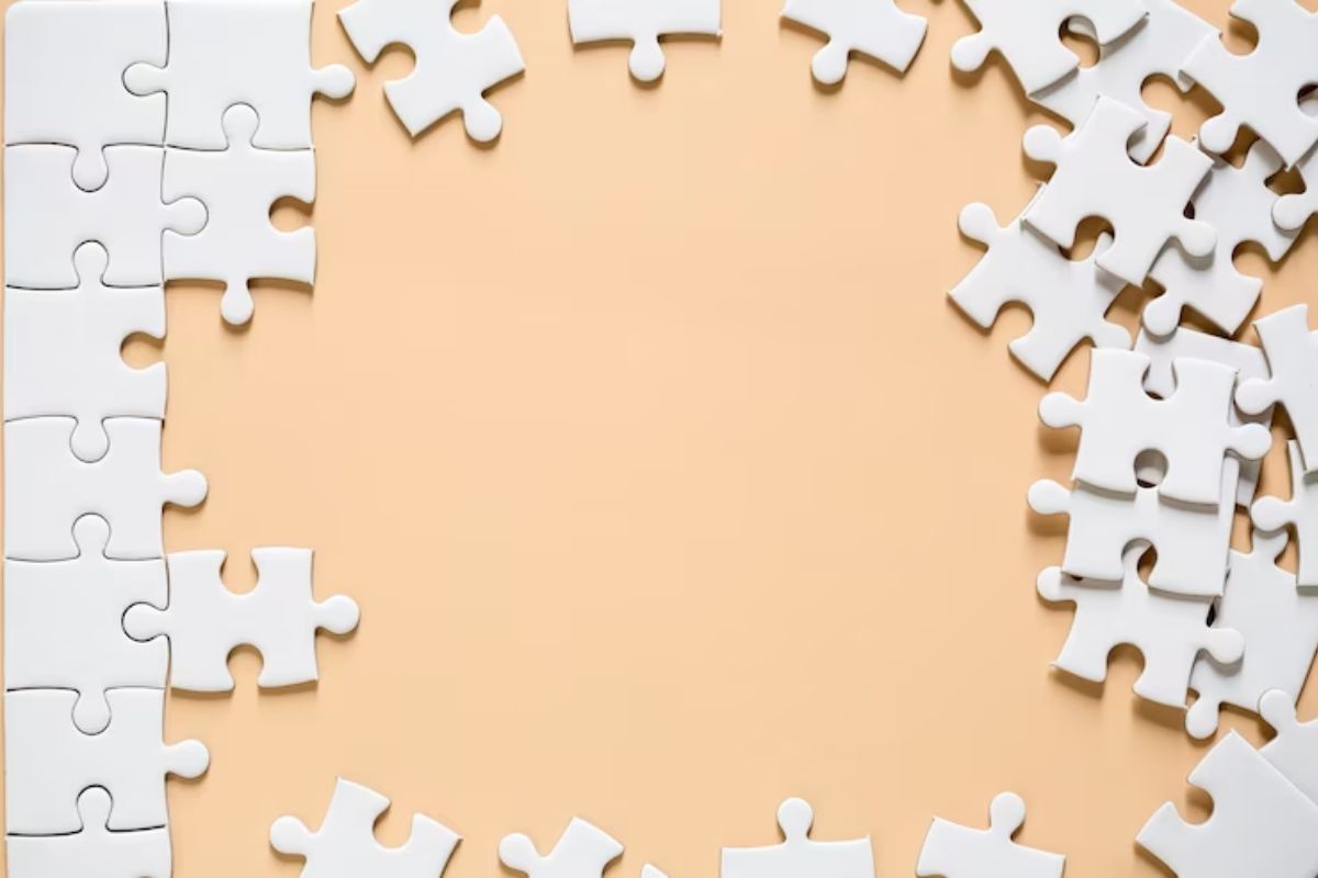 Peças de quebra-cabeças de cor branca com algumas peças laterais no local e outras espalhadas sobre base de cor creme