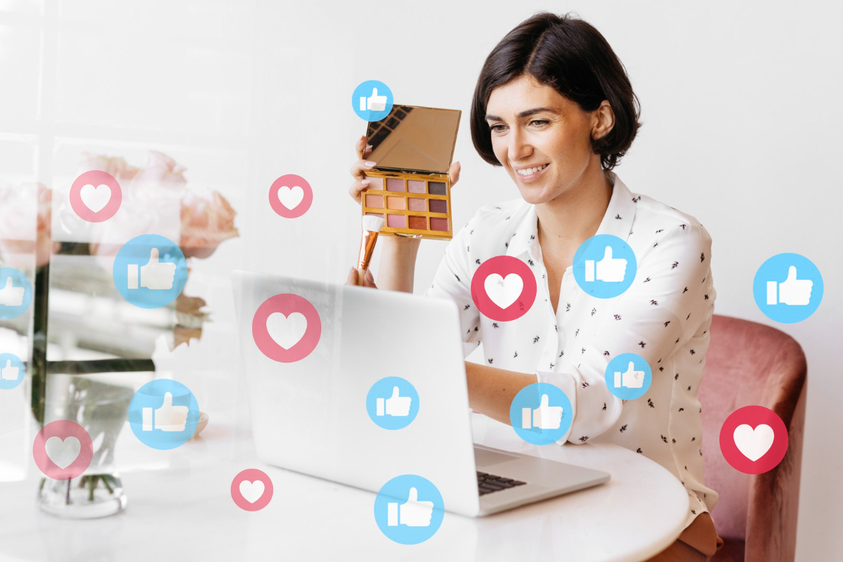 Mulher trabalhando em notebook sobre mesa branca redonda com símbolos de like do Facebook e do Instagram ao redor do aparelho em montagem