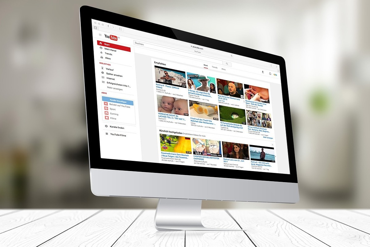 Monitor: YouTube Go YouTube Go aberto em tela de monitor branco sobre mesa branca feita em montagem com fundo da foto em desfoco