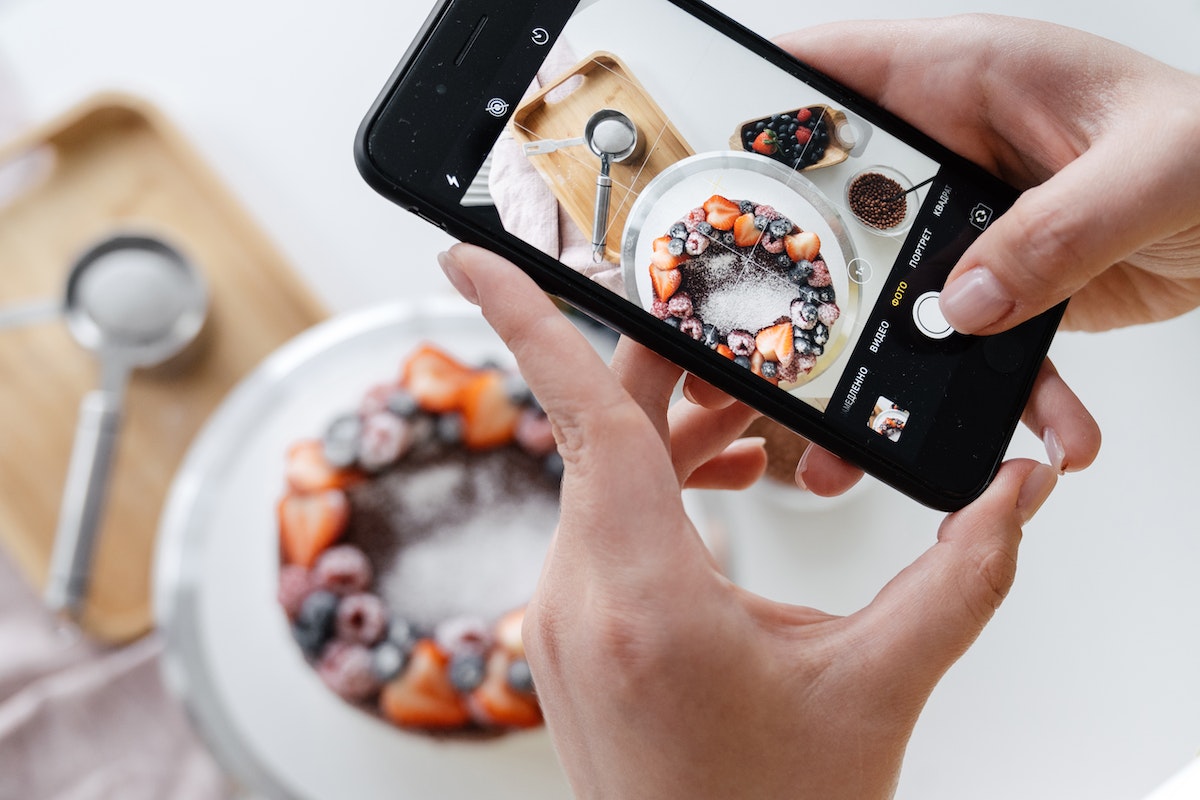 história dos blogs: a imagem mostra uma mulher tirando foto de um prato com bolo decorado. 