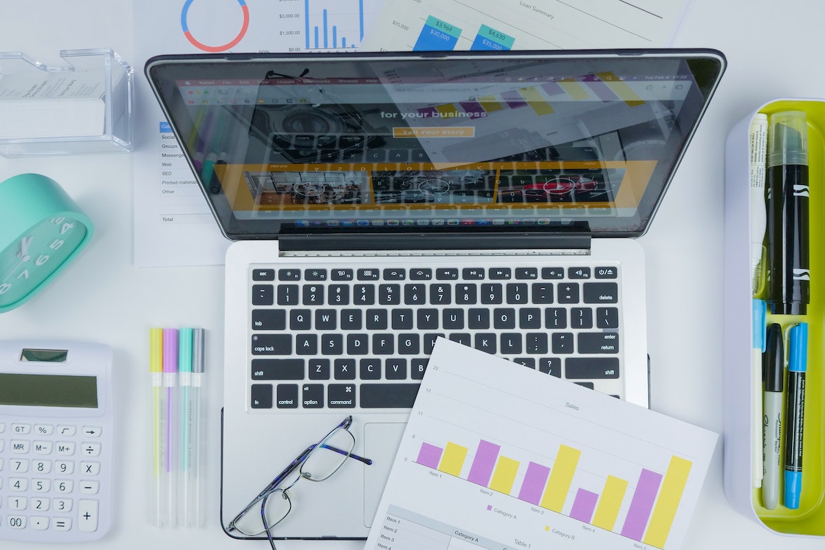 Dicas para começar a monetizar nas redes sociais monetizar nas redes sociais: a imagem mostra um computador com algumas folhas com gráficos