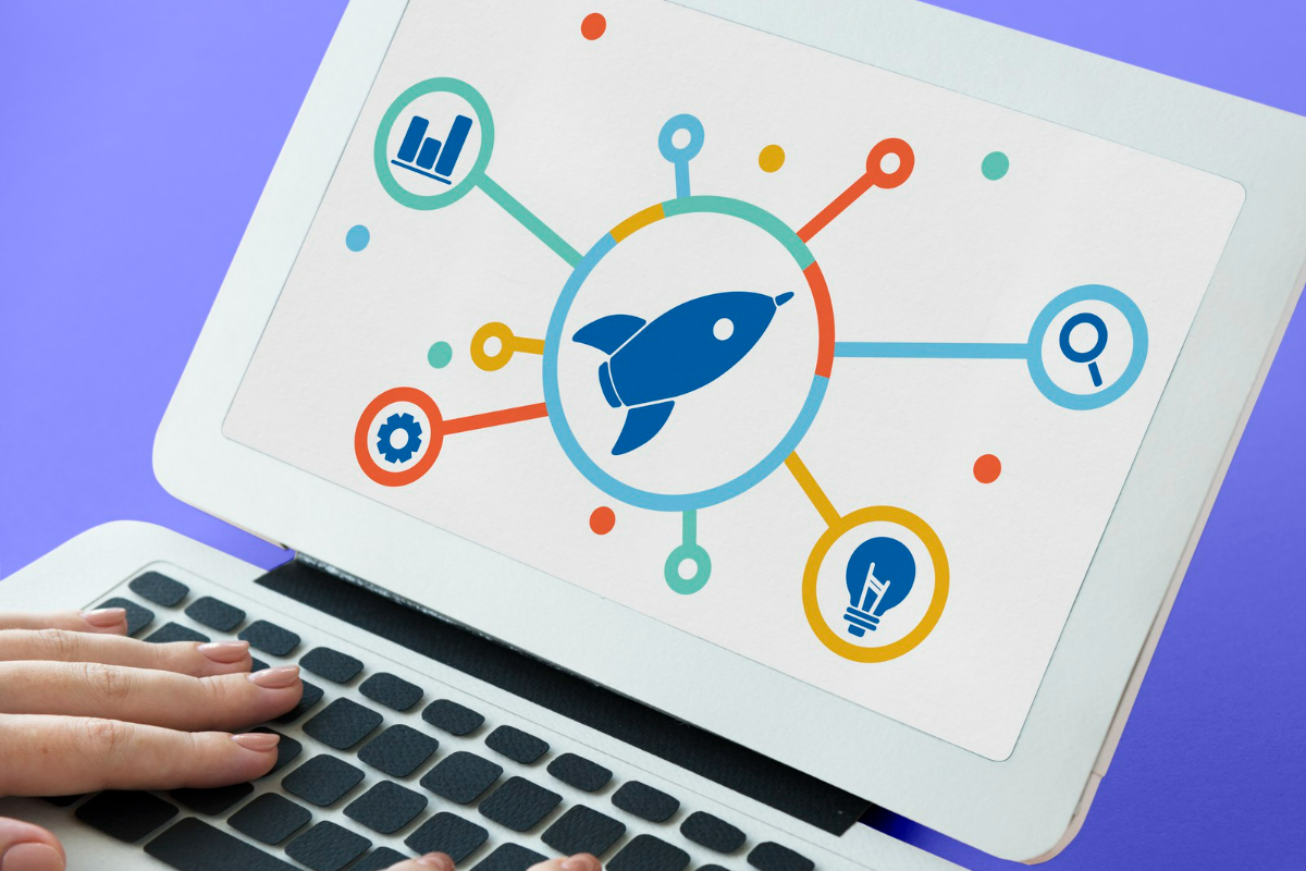 Mãos femininas sobre teclado laptop branco com montagem em sua tela que mostra foguete com linhas que o interliga à outros símbolos web como representação do tema Answer Engine Optimization