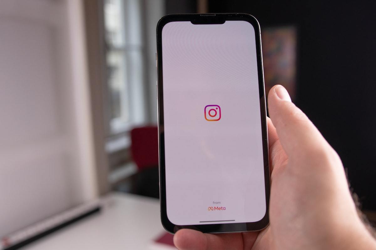 Pessoa usando celular em ambiente interno de casa ou outro local, onde esse exibe tela inicial de aplicativo de rede social onde ele irá selecionar posts para Baixar vídeos do Instagram