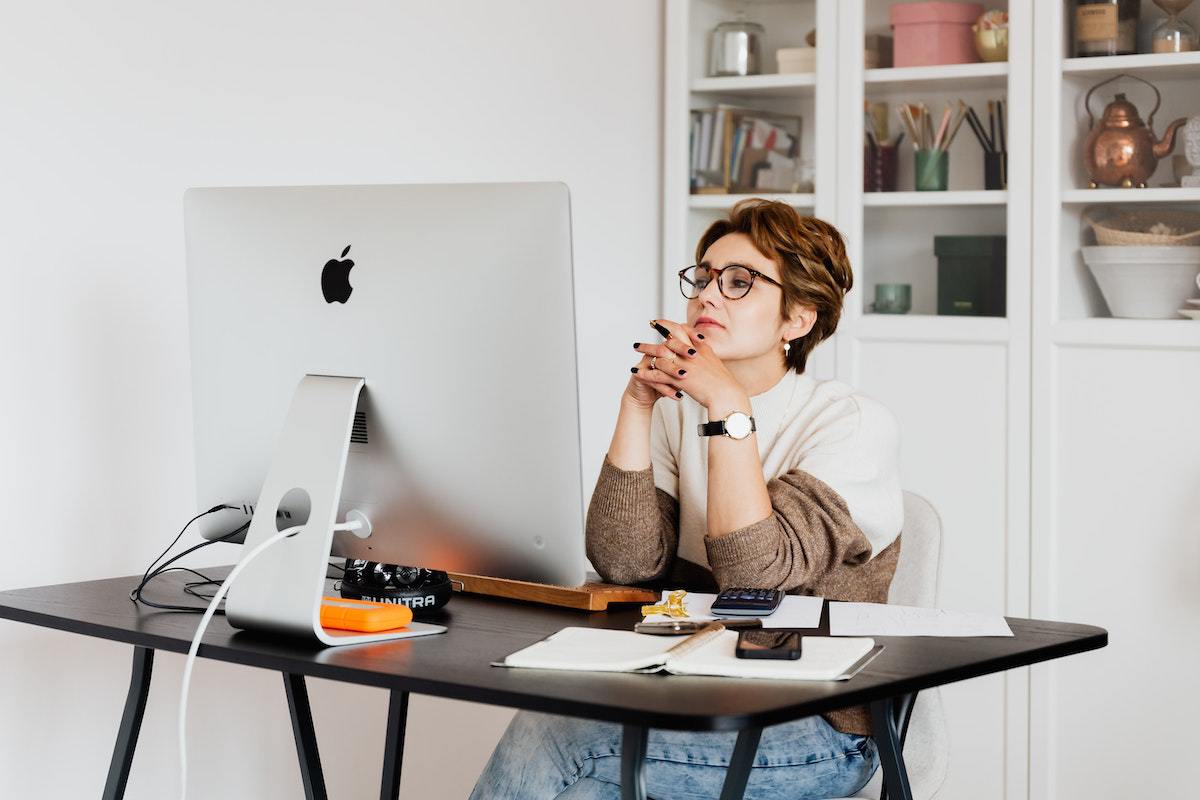 Mulher trabalhando em ambiente análogo à home office usando Buzzsumo em computador sobre mesa escura