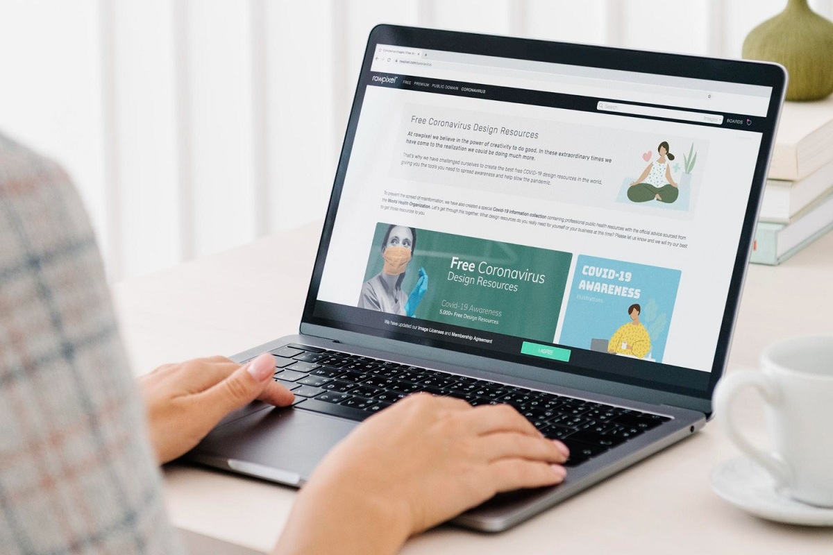 Sites: CMS e Hospedagem Pessoa lendo artigos e notícias em sites por meio de notebook sobre mesa branca