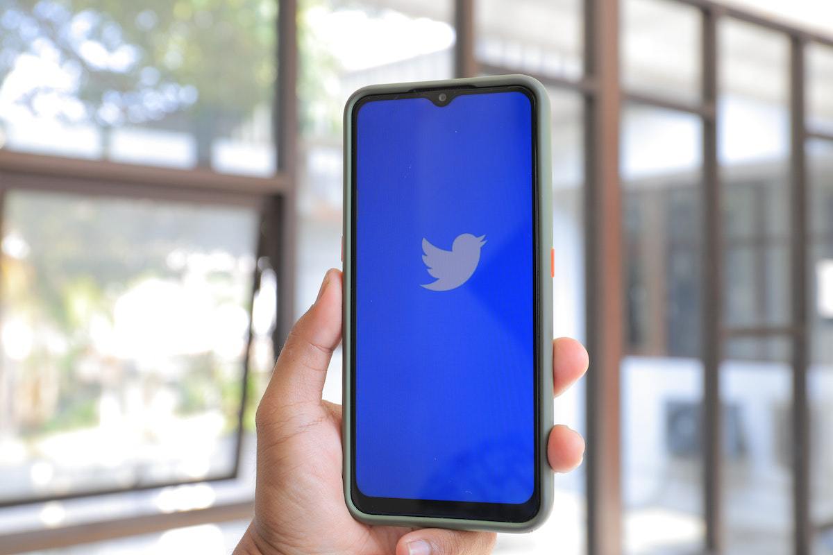 Aplicativo: Campanhas no Twitter Pessoa segurando celular enquanto o mesmo abre aplicativo para execução de Campanhas no Twitter