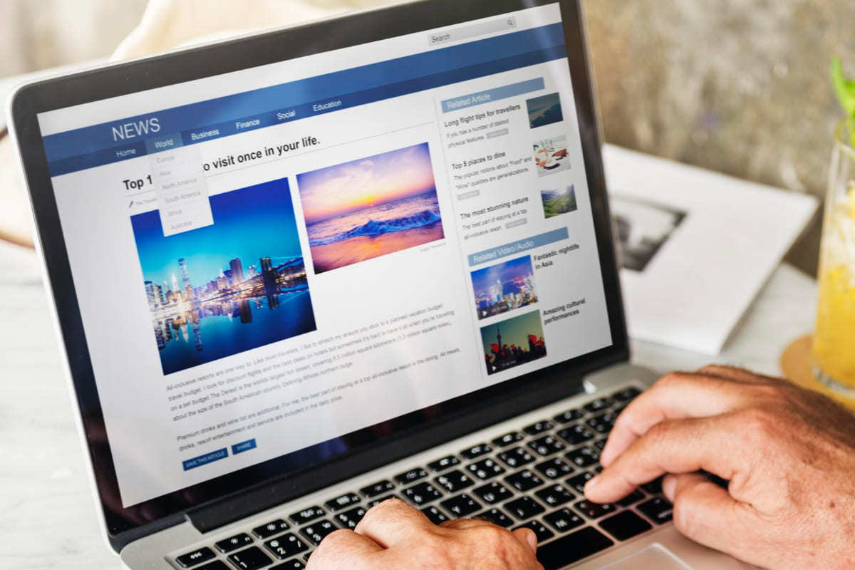 Pessoa acessando site em notebook enquanto lê news no endereço