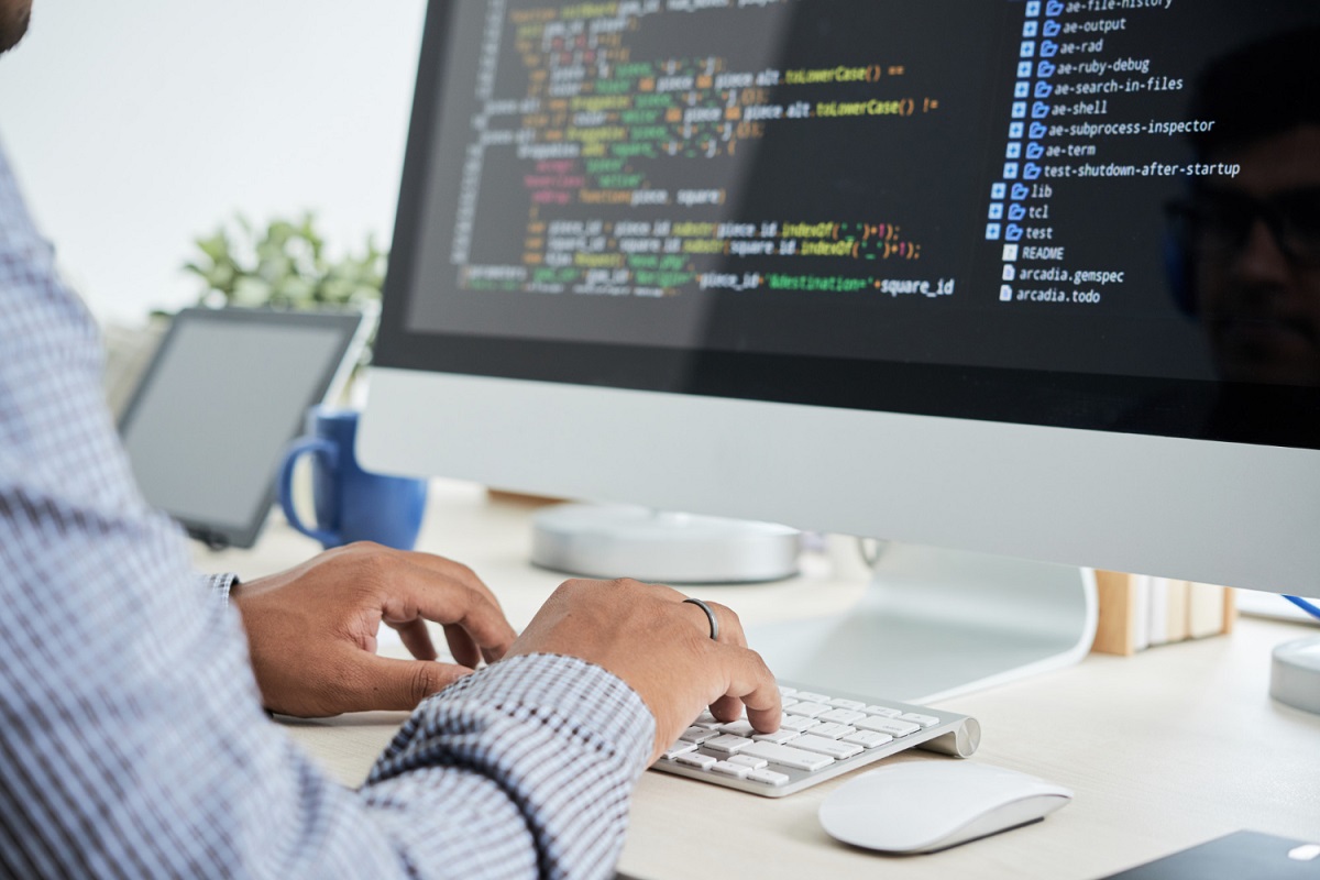 Cientista de dados aplicando Data Science em computador branco sobre mesa de mesma cor em local de trabalho