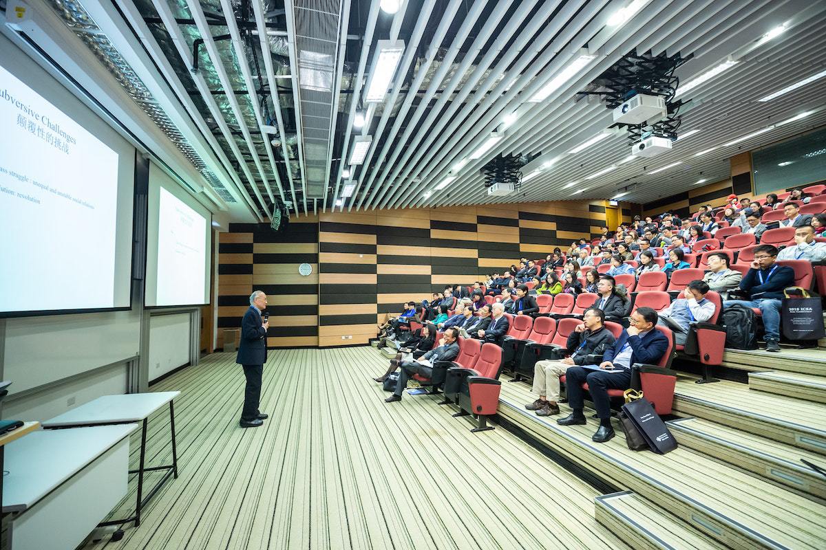 Colaboradores de empresa em auditório sentados em cadeiras enquanto assistem palestra de Diretor de vendas